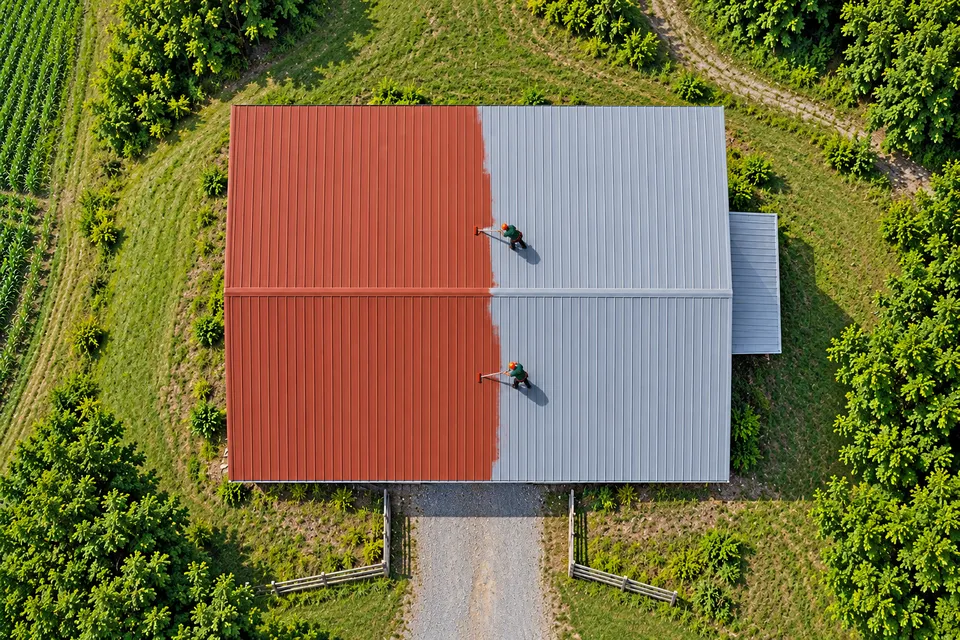 Aerial view of coating work on a metal barn roof